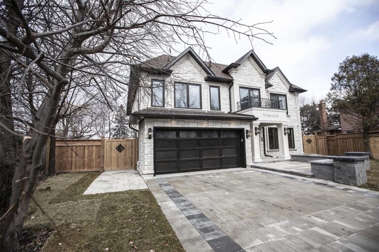 Paver driveway with a dark border, a raised stone planter and a new wood fence and gate at a custom home built by Route Homes (79 Ames Crl)