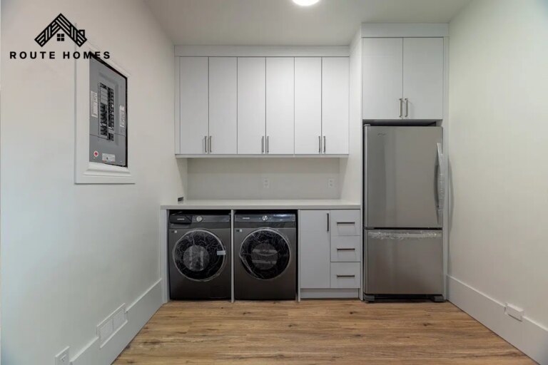 Rental unit with a side-by-side washer and dryer, white cabinets and a stainless fridge at 406 Roncesvalles Ave, renovated by Route Homes