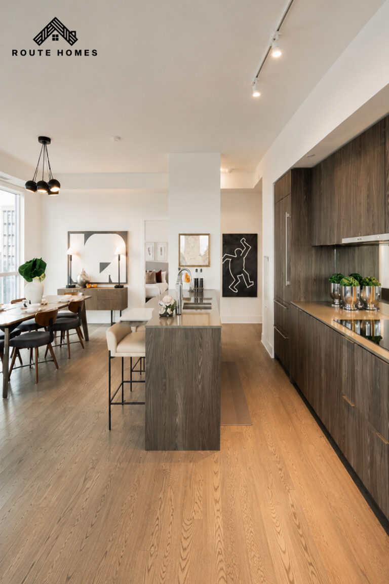 Condo kitchen with a wood-grain island, full-height wood-grain cabinetry and track lighting, open to the dining area, in a Calgary condo unit renovated by Route Homes